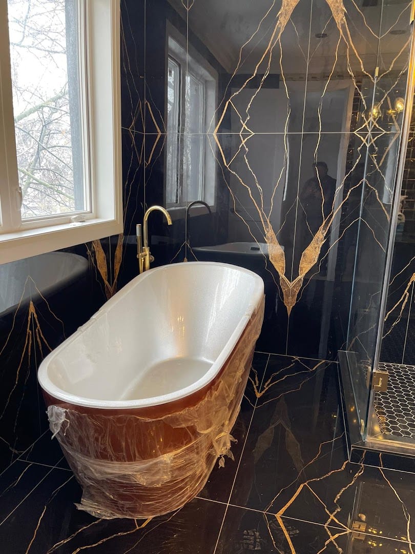 Black and gold marble bathroom with freestanding tub installed by Golden Yak Plumbing