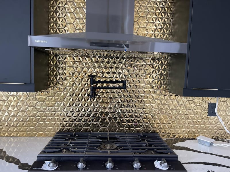 Gold tiled kitchen backsplash with pot filler installation